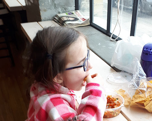 Little girl eating chips and salsa.